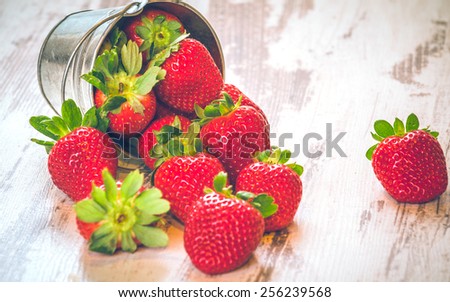 Spring fruits, strawberries in an aluminum bucket on a vintage wooden table.
