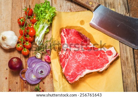 Meat with fresh vegetables, spices and meat cleaver on a wooden table vintage