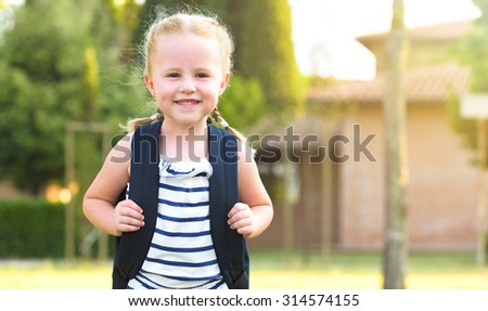 Schoolgirl Returning to school after the holidays, smiling and cheerful, with a rucksack