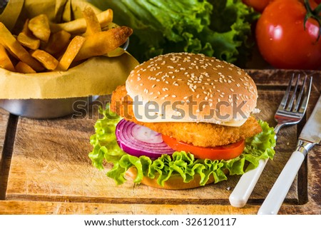 Country-style dish on a wooden table with a chicken burger and fried chips