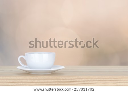 white cup of coffee on pine Wooden Table and bokeh,defocused light background