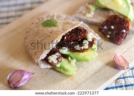 Pita bread with avocado and sun dried tomatoes on the wooden board