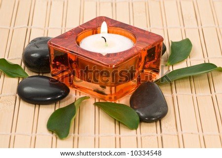 Spa stones with candle and green leaves on bamboo