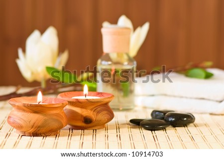 Aromatherapy bottle with stones, towel, candles and flower on bamboo