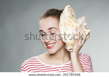 young gorgeous woman closing her eyes in listening to the sound of the ocean made by a shell to her ear