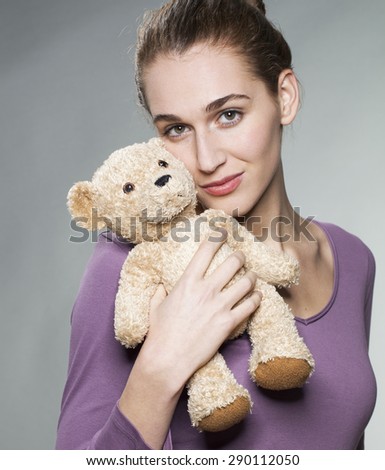 beautiful young blonde woman hugging her teddy bear tightly for tenderness and child memories