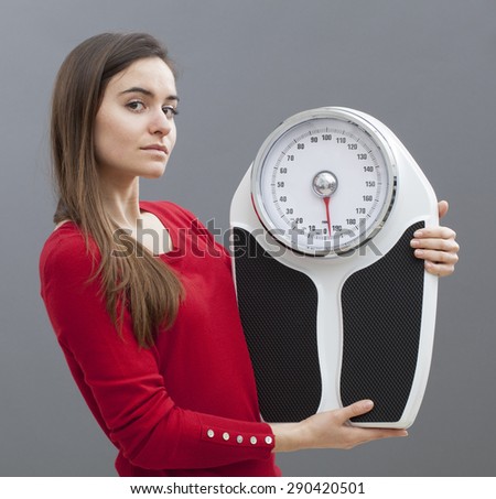 confident young woman with weighting scale in hands for concept of weight loss or weight control