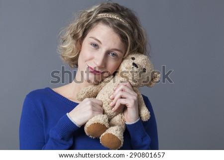 happy young blonde woman hugging her teddy bear with tenderness for nostalgia