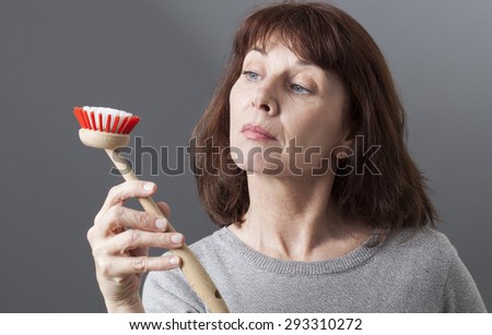beautiful 50s woman displaying dish brush as a house punishment for such a proud lady