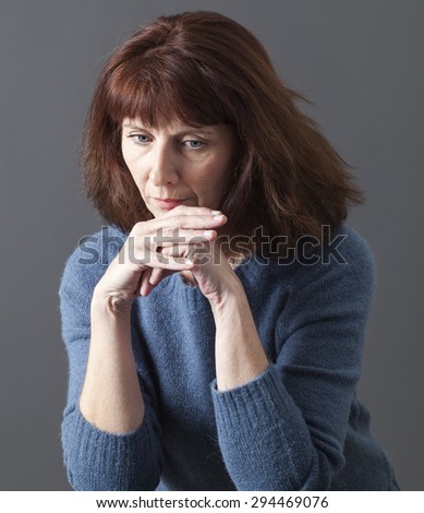 sad 50\'s woman alone with chin resting on hands for reflection, sadness or fatigue due to menopause