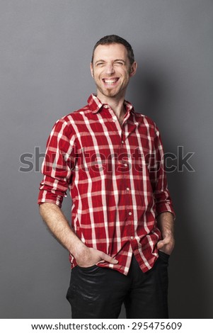 thrilled middle age man with goatee laughing for fun and relaxed attitude with hands in jeans pockets