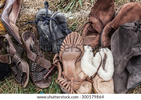 mix of second hand leather women shoes and boots on sale at garage sale on grass for donation, recycling or selling for cheap to cope with fashion and over-consumption