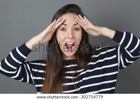 surprise and success concept - amazed 20s woman putting both hands on her face shouting for surprise and happiness