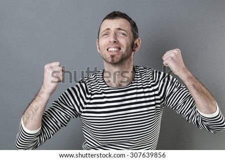 motivation concept - fighting young man wearing a casual striped sweater with fists up for disappointment and frustration