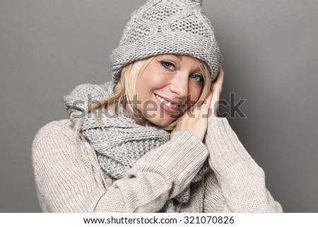 trendy warm winter - cute young blond woman wearing gray wool winter hat and scarf smiling for softness and cozy fashion