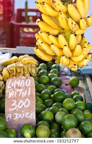 Bunch of bananas and a table with taithi lemon for sale in a brazilian street market.