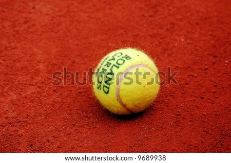 Yellow tennis ball lies on the red clay court of Roland Garros, Paris