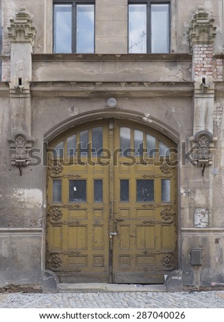 Architectural Detail of Arched Wooden Doors, Closed and Pad Locked, at Entrance of Weathered Abandoned Stone Building in Gorlitz, Germany