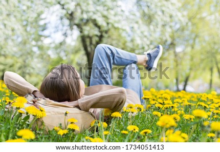 Relaxing woman lying on spring blooming meadow. Girl resting in summer park. Enjoy life, having fun, leisure, relaxation, springtime, lifestyle concept Сток-фото © 