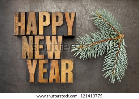Happy New Year! - text in vintage letterpress wood type blocks on a grunge metal background with a branch of Colorado silver spruce