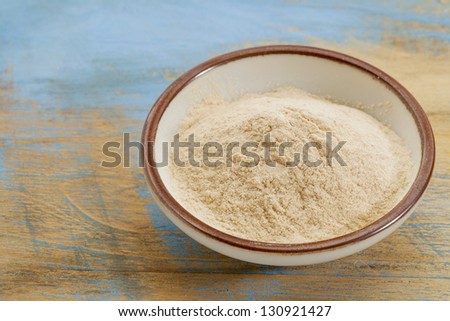 small ceramic bowl of African baobab fruit powder against grunge painted wood background
