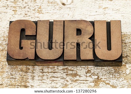 guru word in vintage letterpress wood type blocks against grunge white painted barn wood