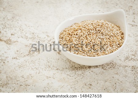 small ceramic bowl of  unhulled sesame seeds against a ceramic tile background with a copy space