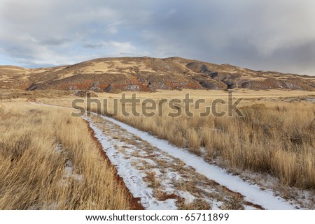 hiking trail on a ranch road with snow and footprints - Red Mountain Open Space in northern Colorado (Larimer County), fall scenery with dry grass