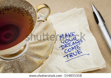 make your dreams come true - motivational slogan on a napkin with cup of tea