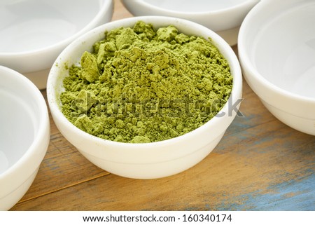 moringa leaf powder in a small bowl among empty white bowls