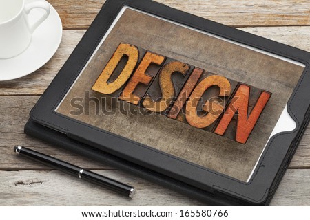 design word in vintage letterpress wood type on a digital tablet with a cup of coffee