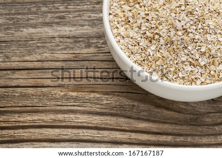 oat bran - a ceramic bowl on grained wood background