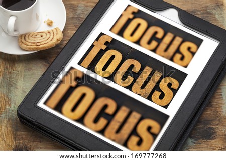 focus word in and out of focus  - text in vintage letterpress wood type on a digital tablet with a cup of coffee