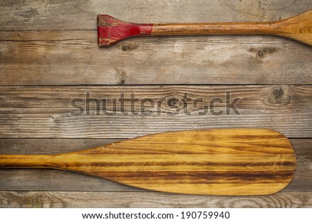 blade and grip of wooden canoe paddle against rustic wood background with a copy space