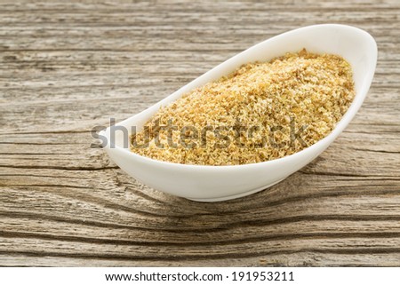 flax seed meal in a small ceramic bowl against grained wood