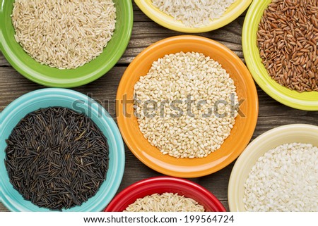 a variety of rice grains on colorful ceramic bowls against a grained wood