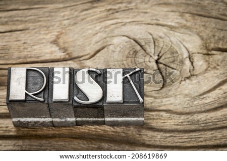 risk word in letterpress metal type printing blocks against weathered grained wood