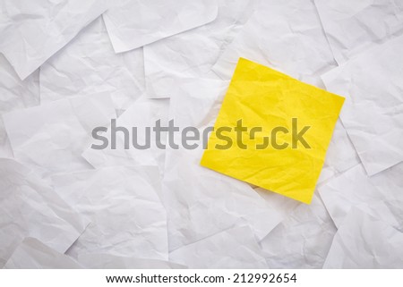 blank yellow sticky note against background of white crumpled notes