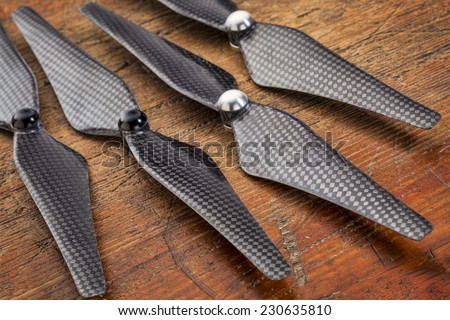 set  of four carbon fiber self-tightening propellers for a quadcopter drone against grunge wood