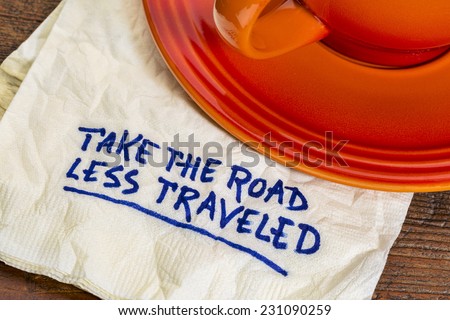 take the road less traveled - handwriting on  a napkin with a cup of coffee