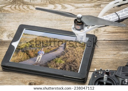 drone aerial photography concept - reviewing aerial picture (drone operator in a field) on a digital tablet with a drone rotor and radio control transmitter,