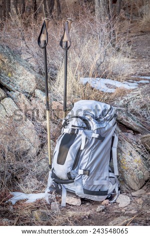 hiking concept - backpack and trekking poles in a rocky terrain