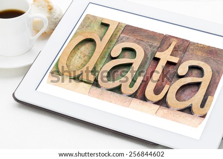 information age concept - data word in letterpress wood type on a digital tablet with a cup of coffee