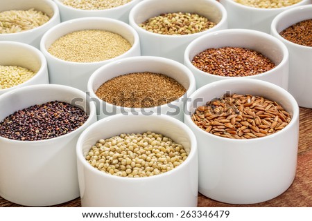 healthy, gluten free grains collection (quinoa, brown rice, millet, amaranth, teff, buckwheat, sorghum), small round bowls against rustic wood