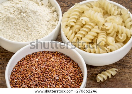 gluten free quinoa grain, flour and pasta on small ceramic bowls - healthy eating concept