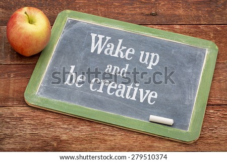 Wake up and be creative  - inspirational positive words on a slate blackboard against red barn wood