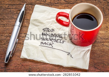 stop holding yourself back - motivational handwriting on a napkin with a cup of coffee