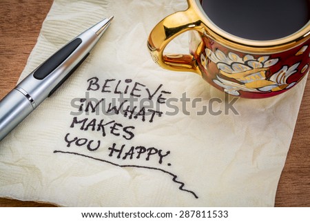 Believe in what makes you happy - handwriting on a napkin with cup of coffee