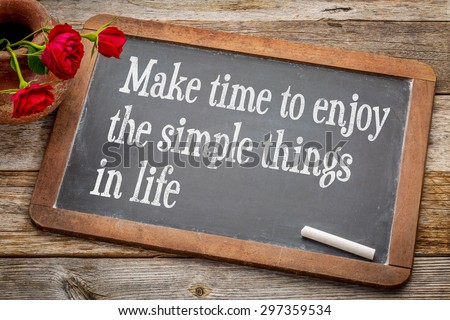 Make time to enjoy the simple things  inspirational advice - white chalk text on a vintage slate blackboard with red roses against rustic wood
