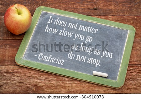 It does not matter how slow you go as long as you don not stop - Confucius quote on persistence- words on a slate blackboard against red barn wood